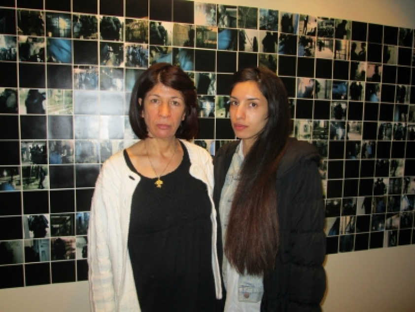 Rehab Nazzal with her daughter Rana Nazzal in front of photos of a raid on Palestinian prisoners. Smiling didn't seem appropriate given the context.